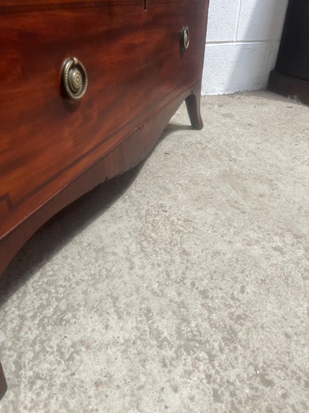 A nineteenth-century mahogany chest of three full-width drawers featuring brass ring handles, boxwood string inlay, and splayed bracket feet. View IX