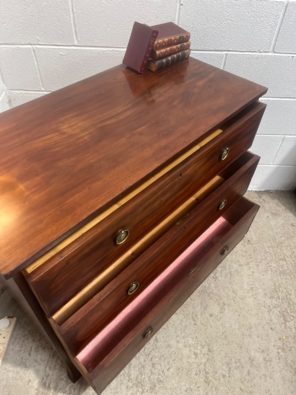 A nineteenth-century mahogany chest of three full-width drawers featuring brass ring handles, boxwood string inlay, and splayed bracket feet. View X