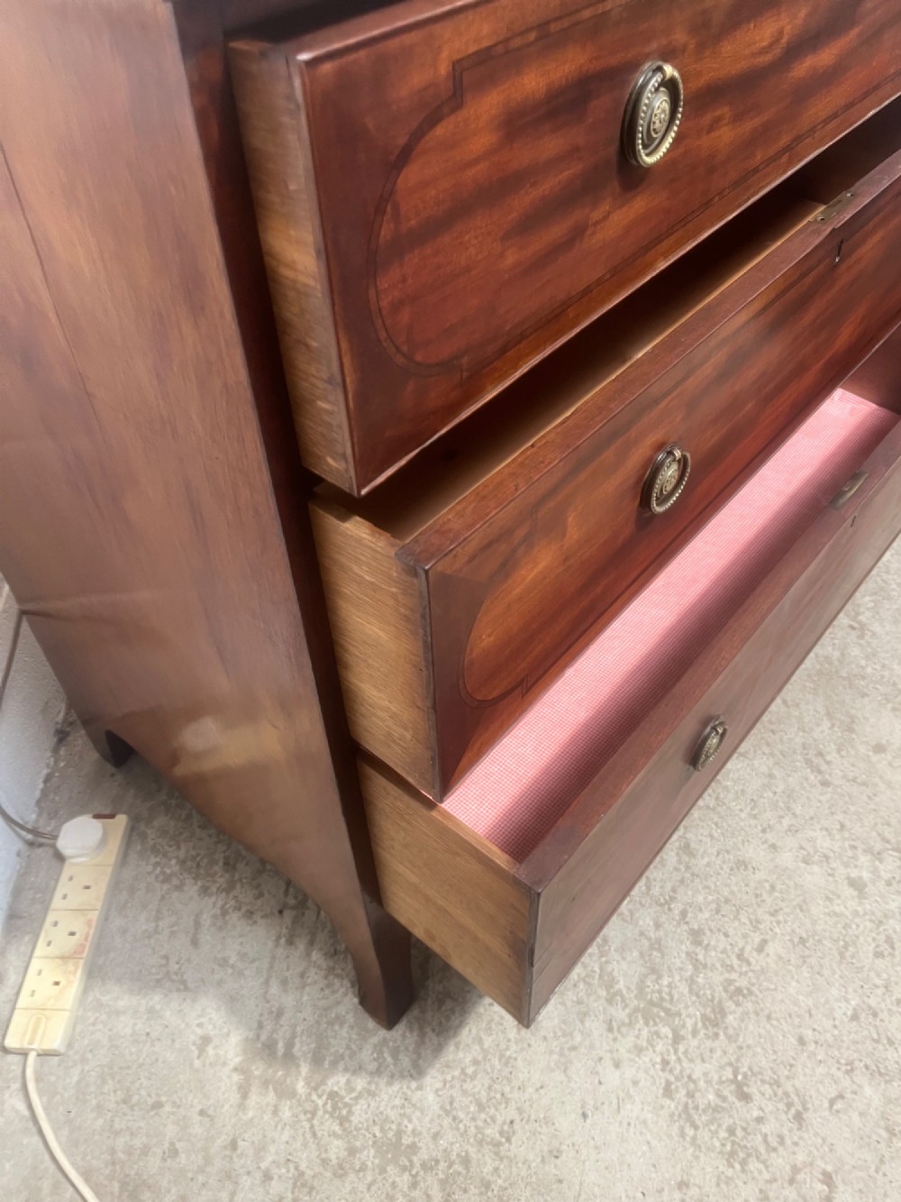 A nineteenth-century mahogany chest of three full-width drawers featuring brass ring handles, boxwood string inlay, and splayed bracket feet. View XI