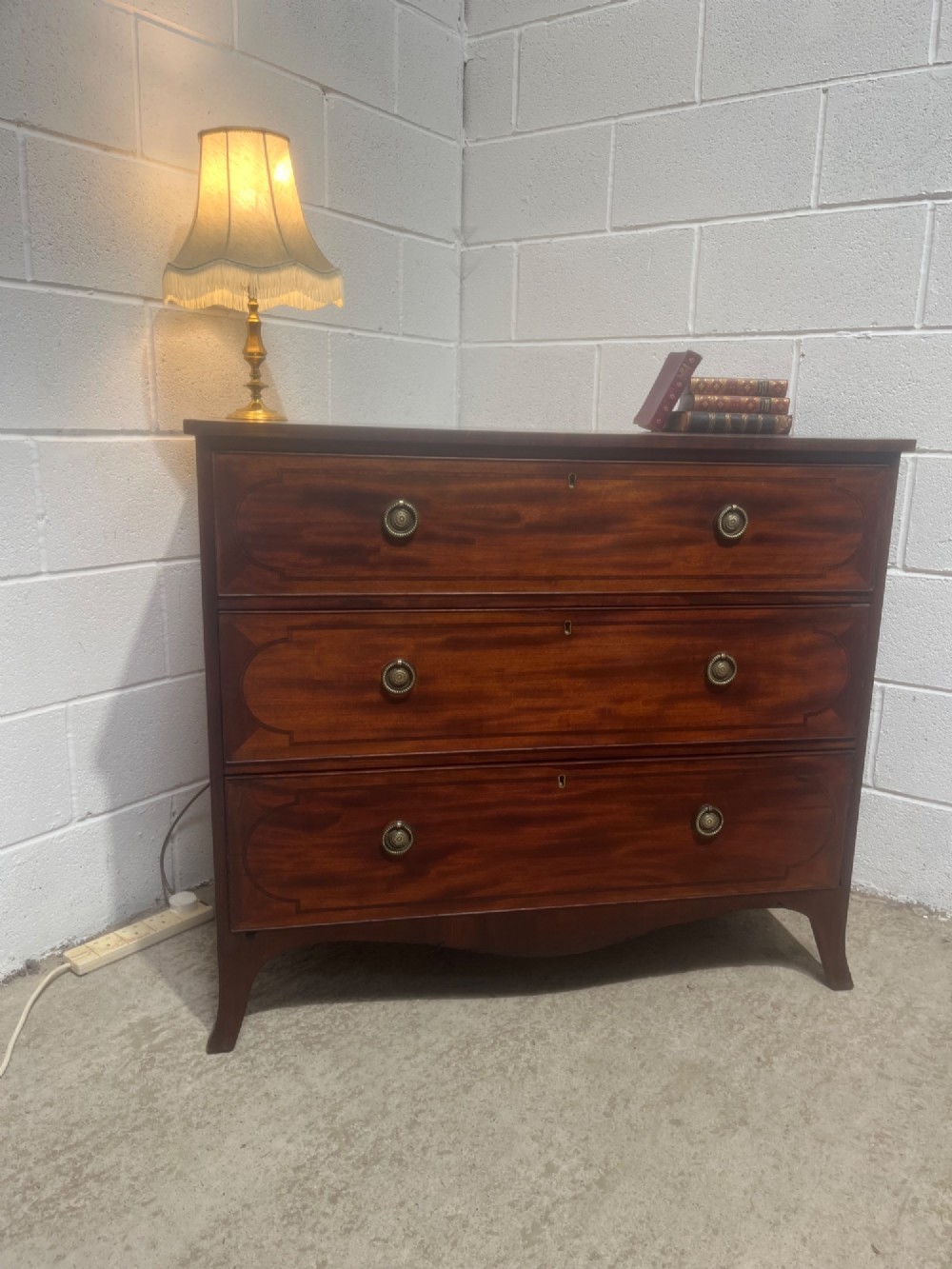 A nineteenth-century mahogany chest of three full-width drawers featuring brass ring handles, boxwood string inlay, and splayed bracket feet. View XII