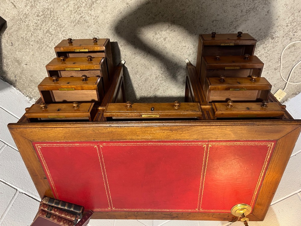 A 19th-century mahogany free-standing pedestal desk featuring a red leather top inset, multiple drawers with turned knobs, and brass castors. View XII