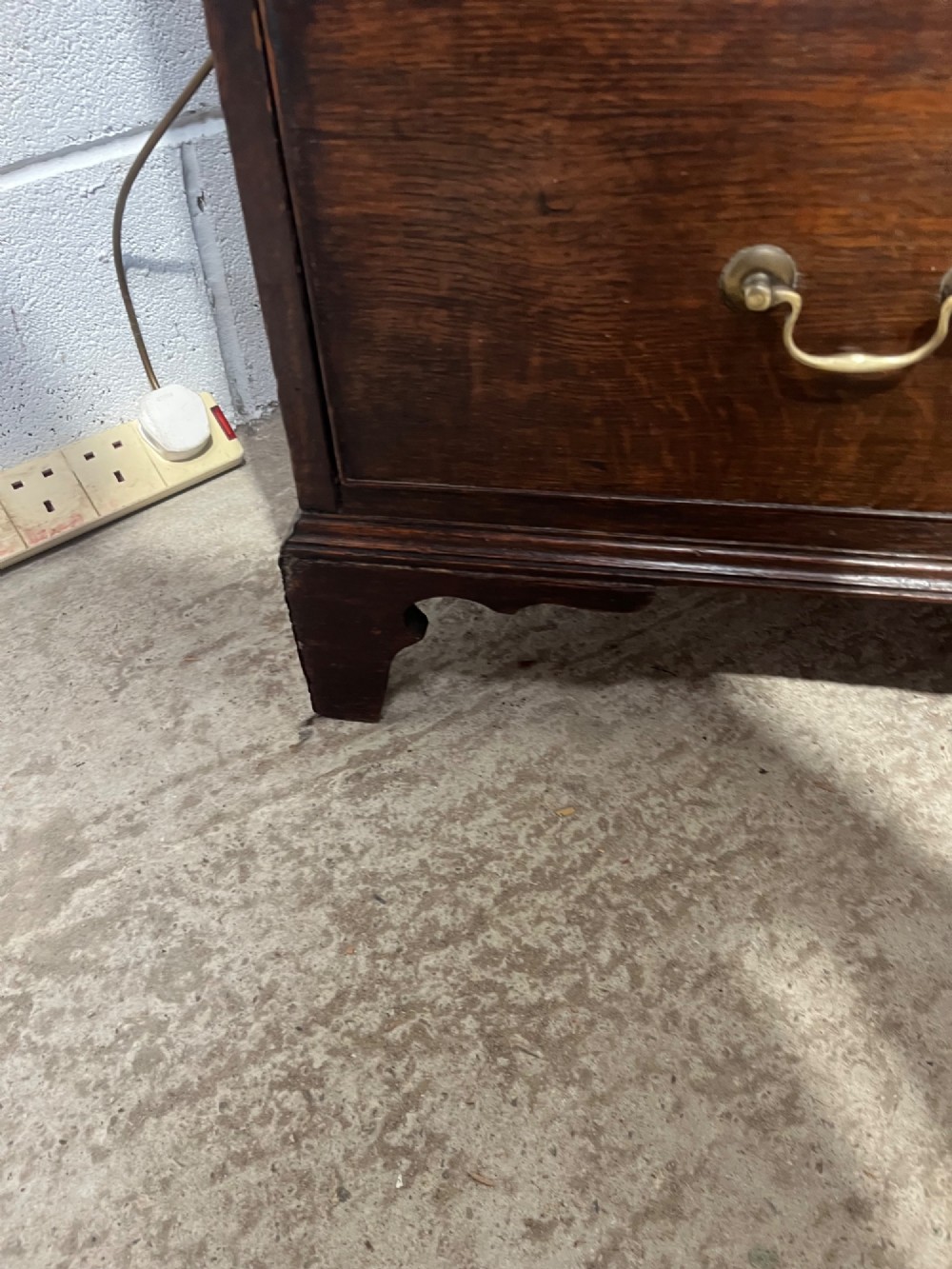 An antique Georgian dark oak chest of drawers with two short drawers above three long drawers, featuring brass swan-neck handles and bracket feet. View VIII
