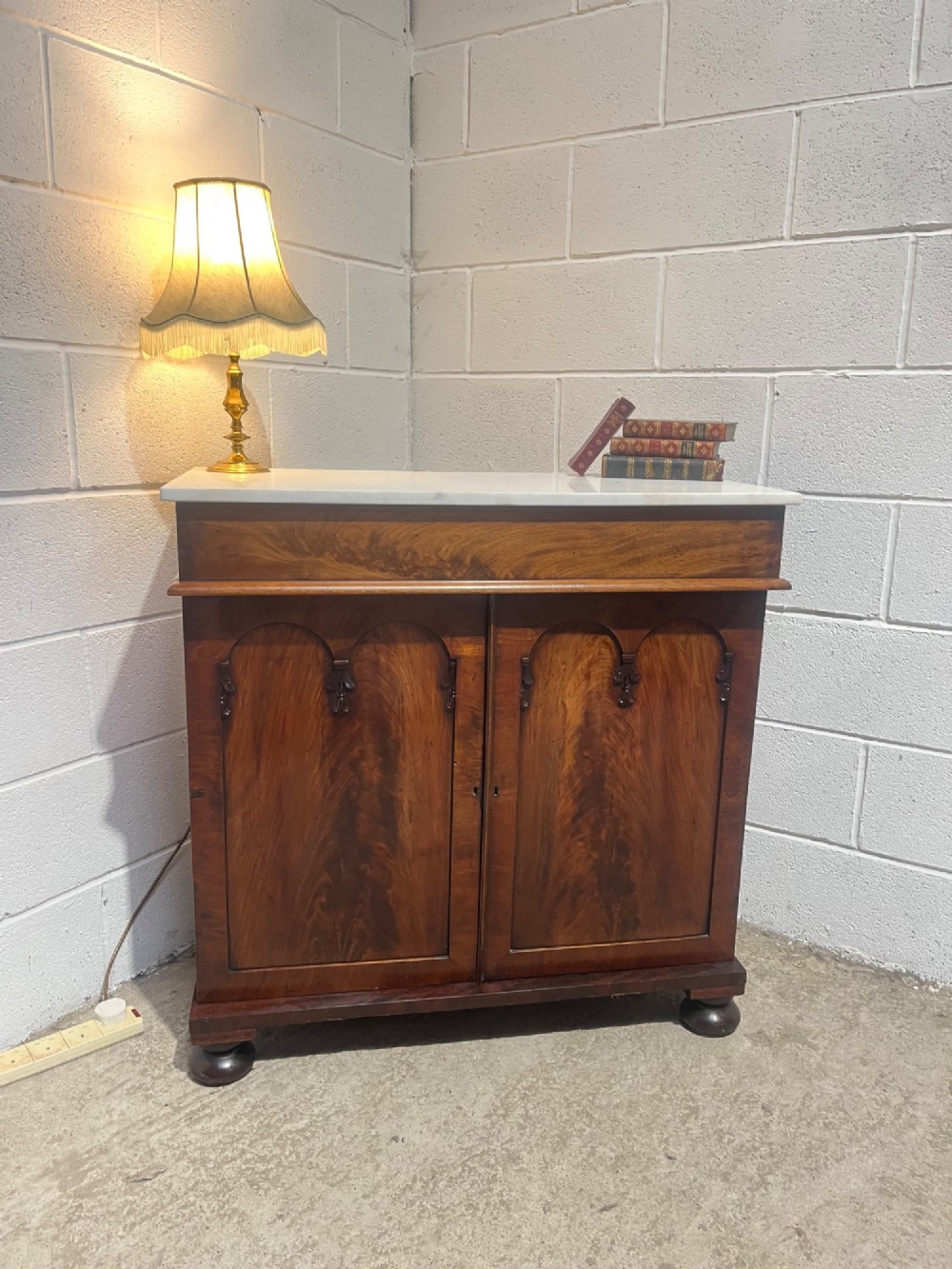 A 19th-century mahogany cupboard featuring twin arched panel doors, flattened bun feet, and a fitted white marble top. View III