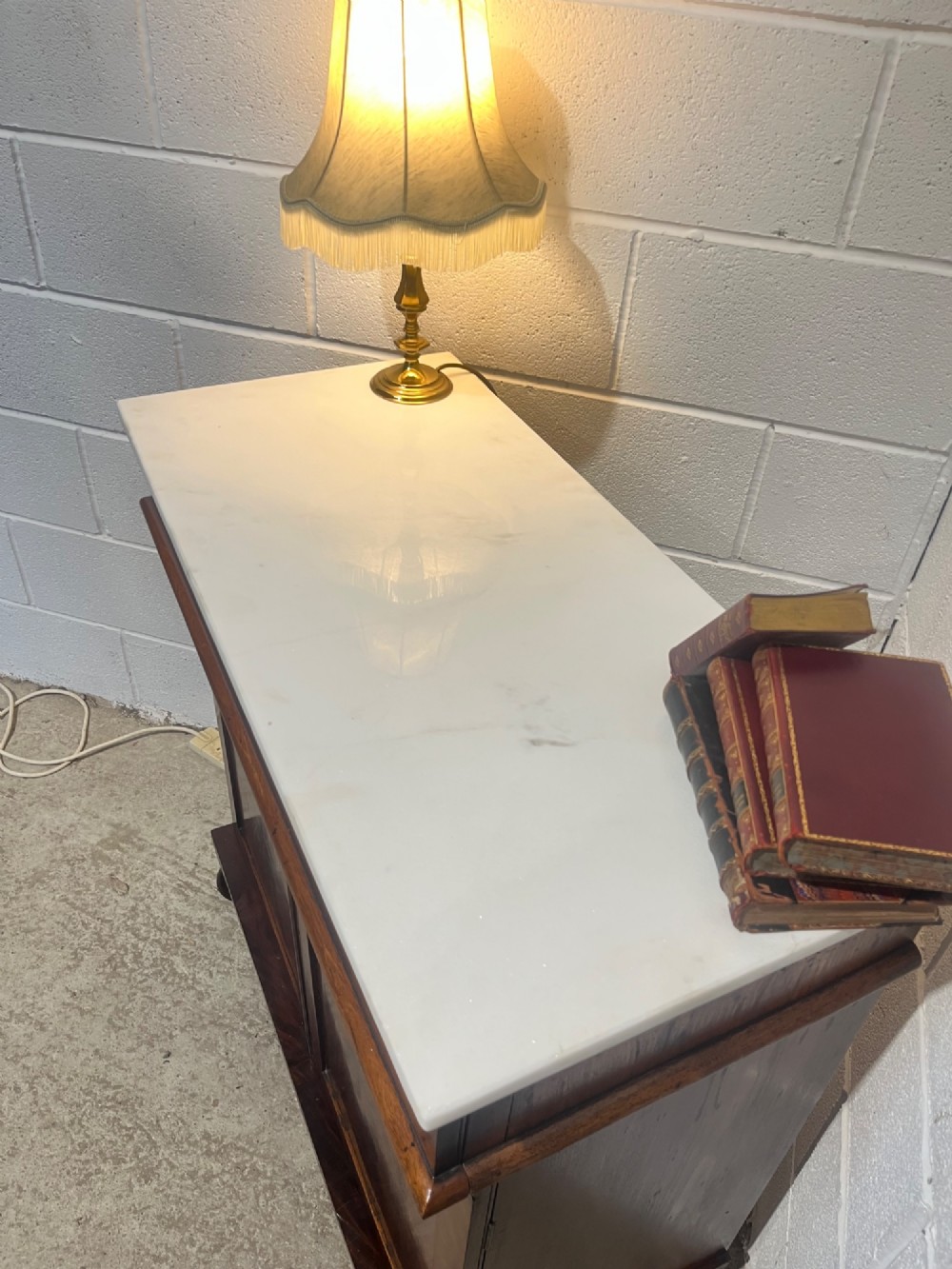 A 19th-century mahogany cupboard featuring twin arched panel doors, flattened bun feet, and a fitted white marble top. View VII
