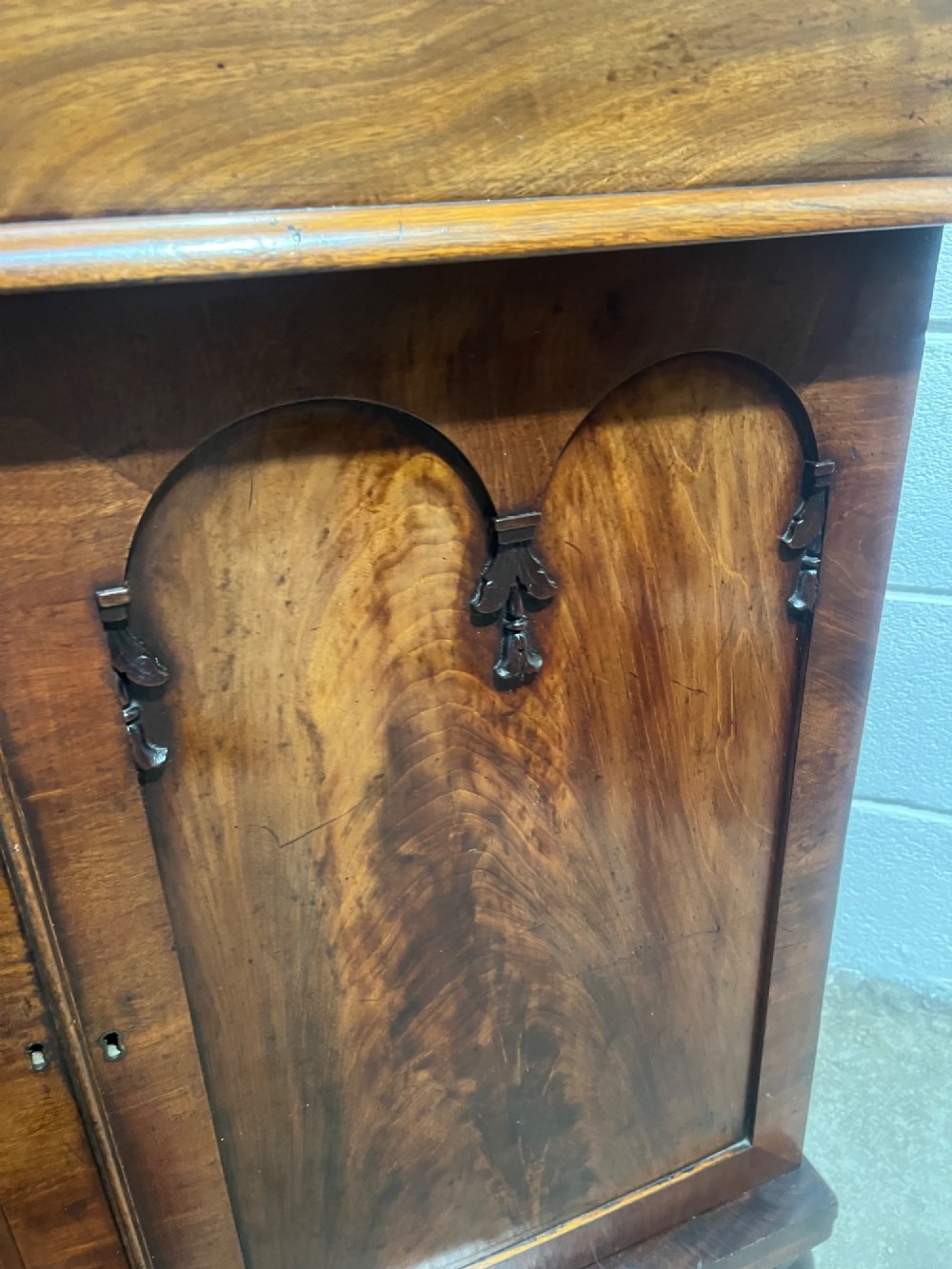 A 19th-century mahogany cupboard featuring twin arched panel doors, flattened bun feet, and a fitted white marble top. View XI