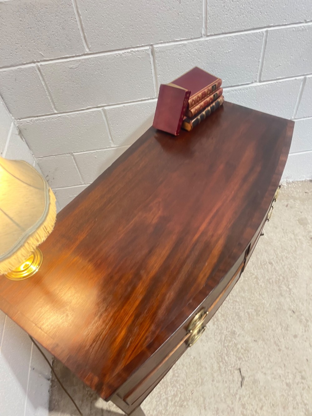 A Georgian mahogany bowfront hall table featuring four drawers with brass handles and tapered square legs on brass castors. View VII