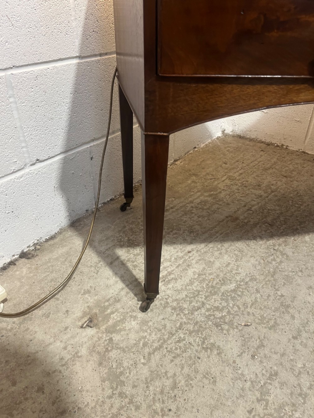 A Georgian mahogany bowfront hall table featuring four drawers with brass handles and tapered square legs on brass castors. View VIII