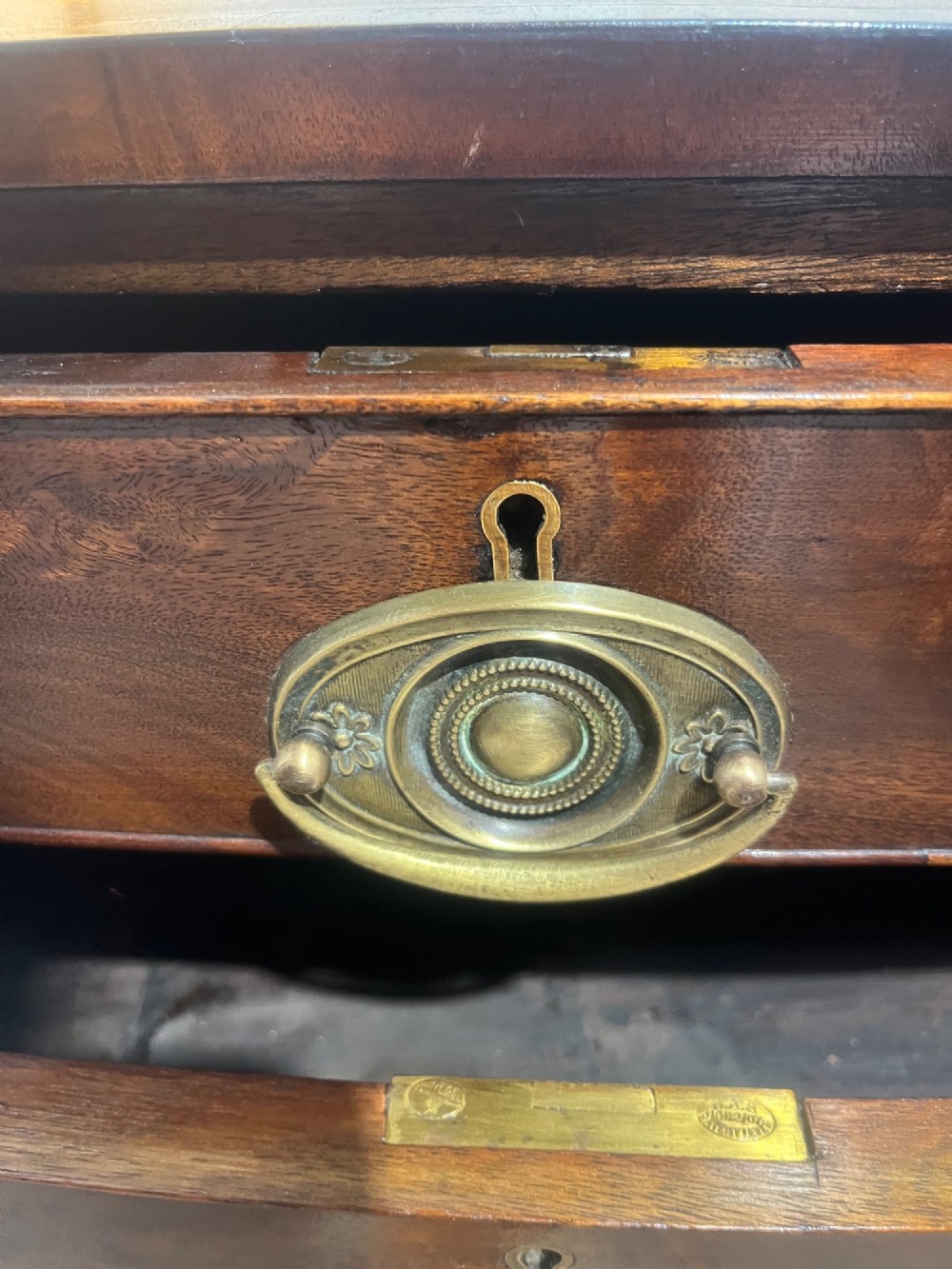 A Georgian mahogany bowfront hall table featuring four drawers with brass handles and tapered square legs on brass castors. View X