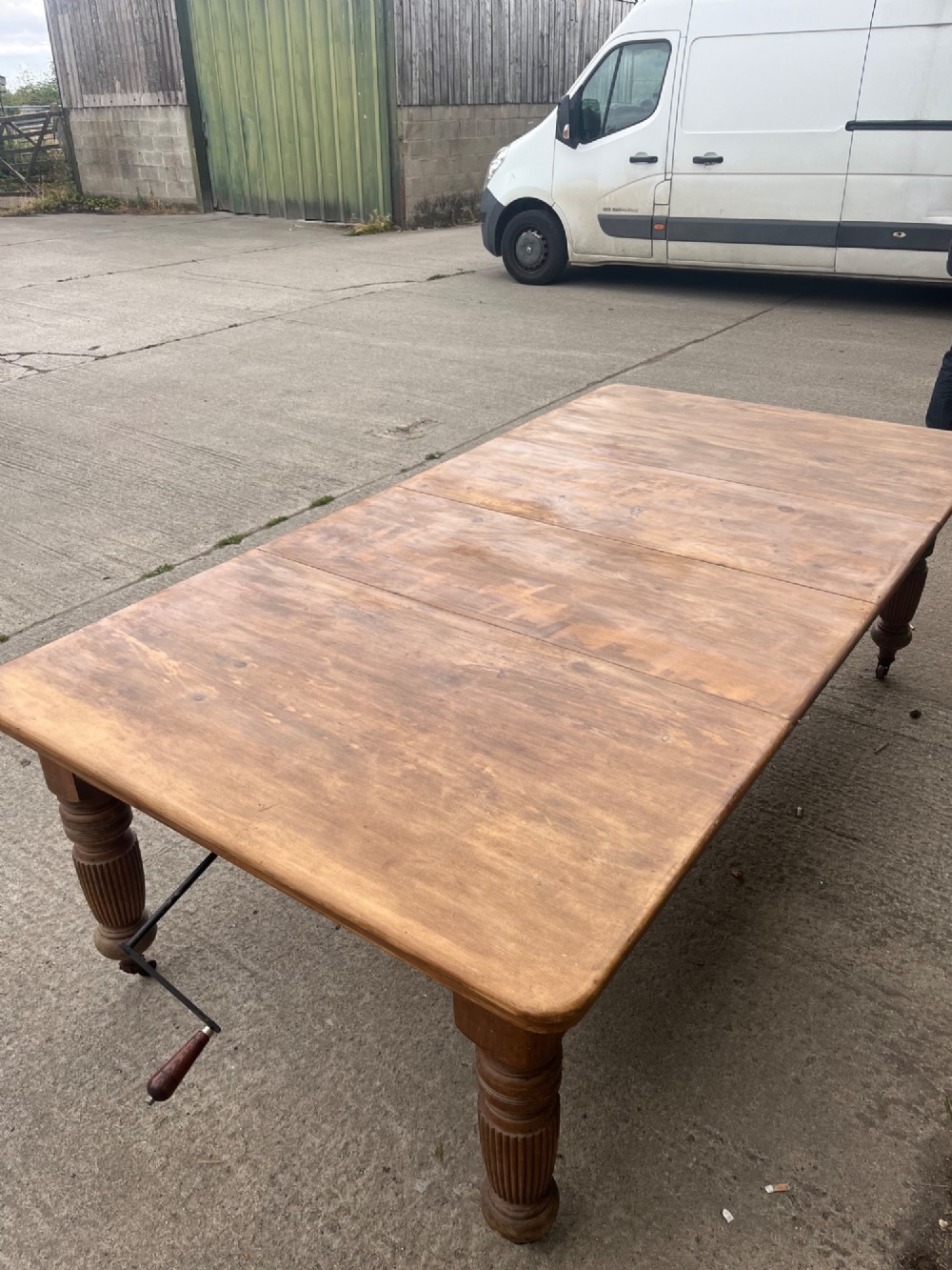 An antique 19th-century pine wind-out extending dining table with turned legs and metal castors. View IV