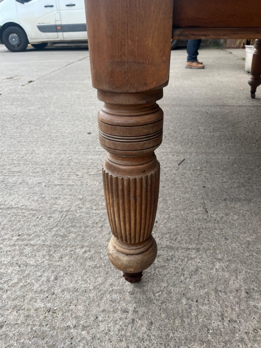An antique 19th-century pine wind-out extending dining table with turned legs and metal castors. View V