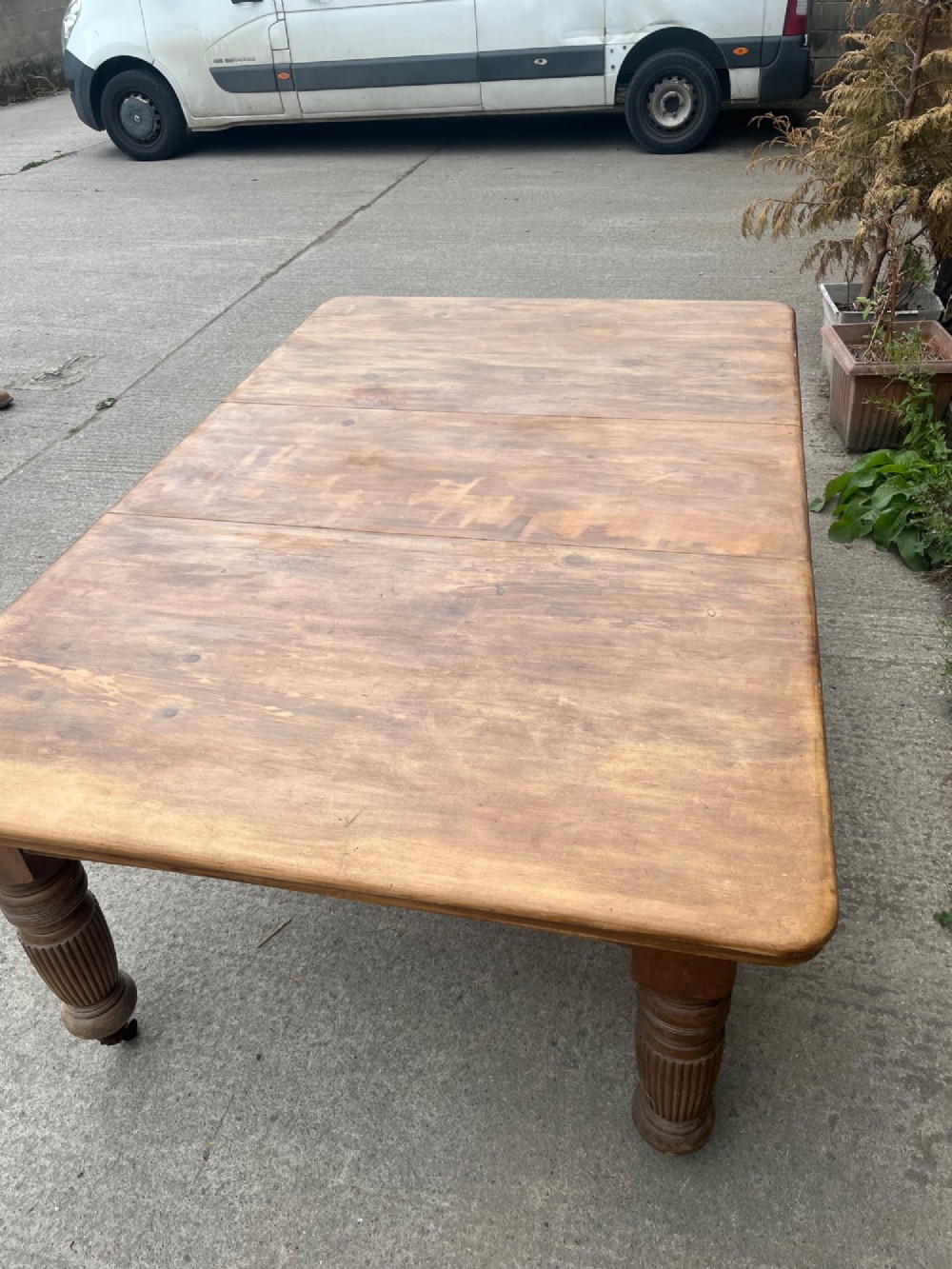 An antique 19th-century pine wind-out extending dining table with turned legs and metal castors. View VI
