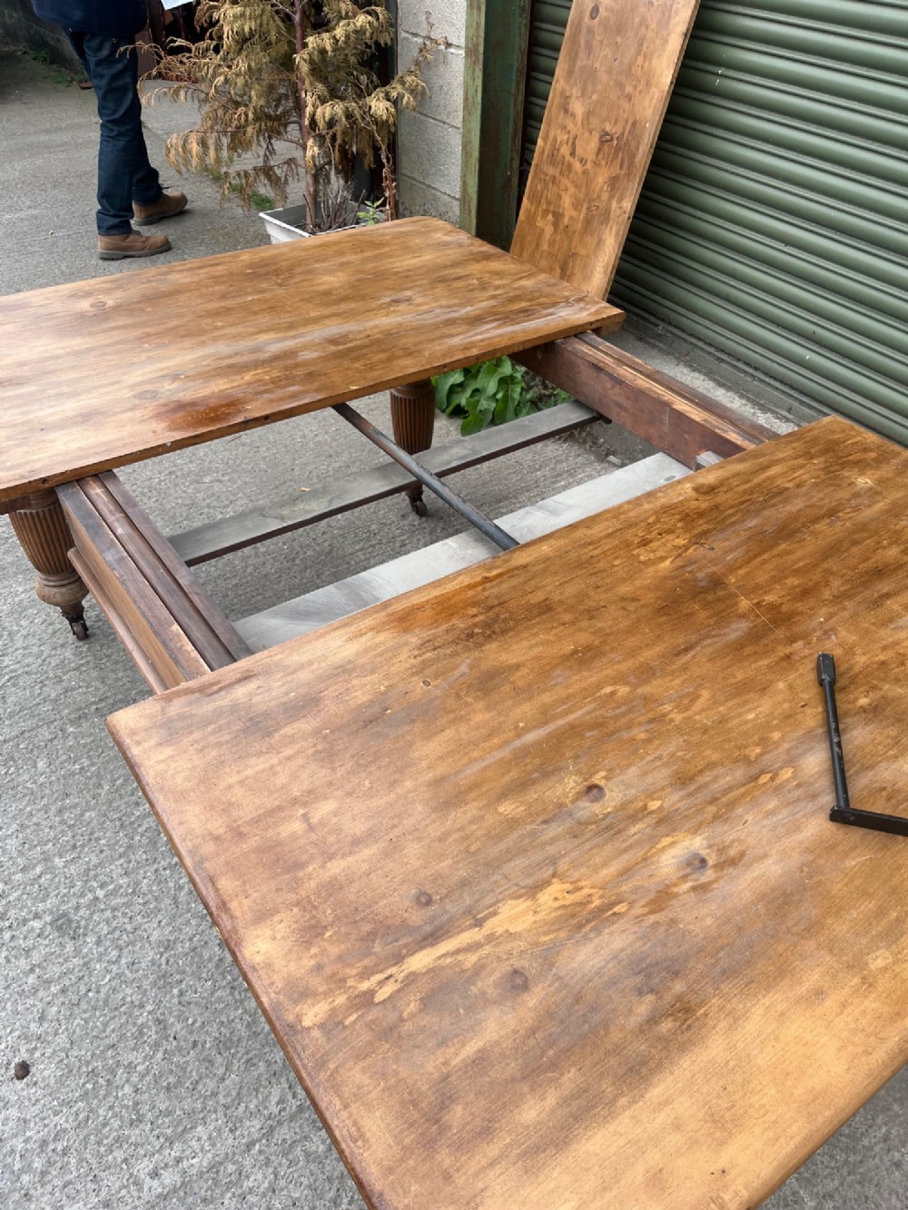 An antique 19th-century pine wind-out extending dining table with turned legs and metal castors. View VII