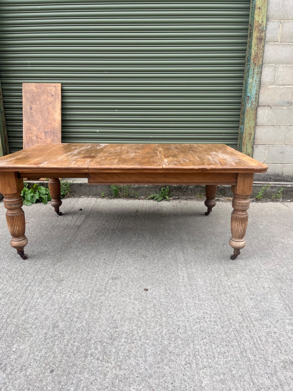 An antique 19th-century pine wind-out extending dining table with turned legs and metal castors. View VIII