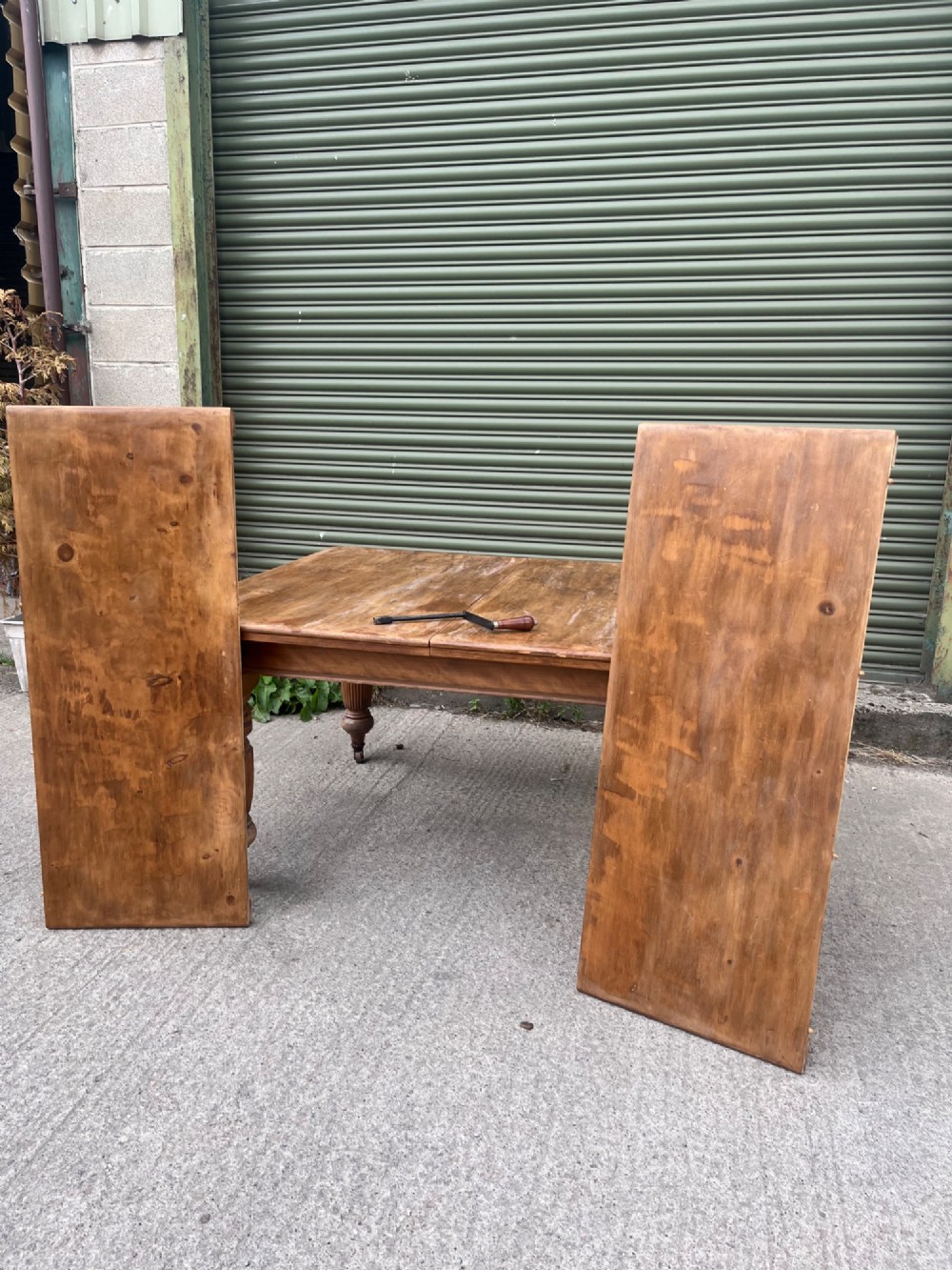 An antique 19th-century pine wind-out extending dining table with turned legs and metal castors. View IX