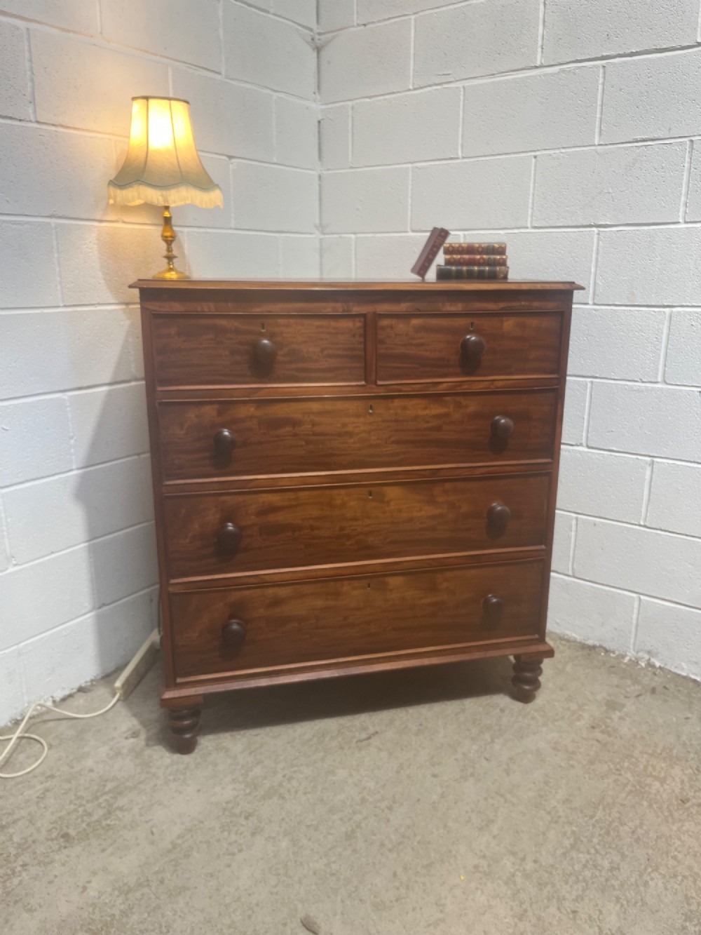 A 19th-century mahogany chest of drawers with a two-over-three drawer configuration, turned wooden knobs, and turned bun feet.