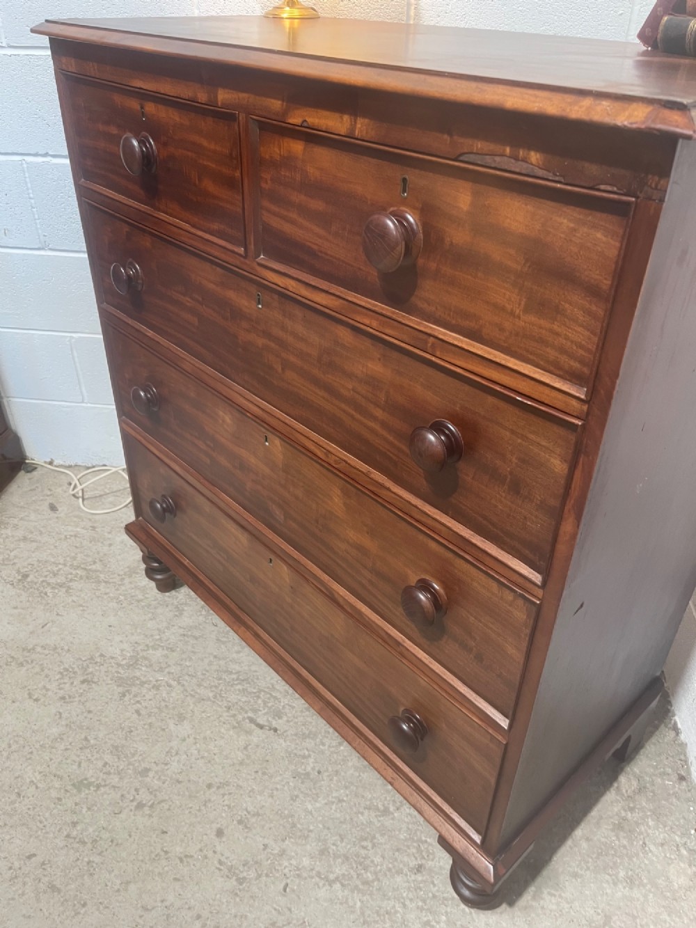 A 19th-century mahogany chest of drawers with a two-over-three drawer configuration, turned wooden knobs, and turned bun feet. View VI