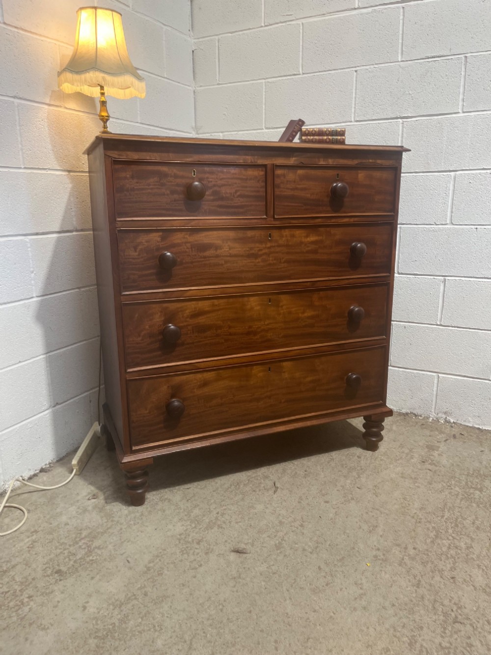 A 19th-century mahogany chest of drawers with a two-over-three drawer configuration, turned wooden knobs, and turned bun feet. View IX