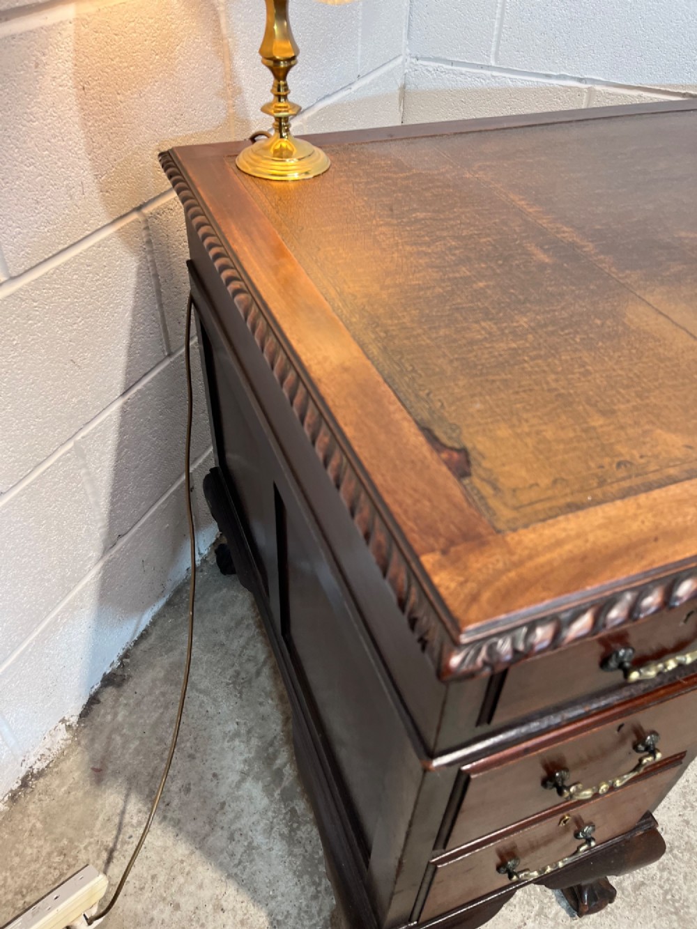 An early 20th-century dark mahogany pedestal writing desk featuring an inset leather top, brass swan-neck handles, seven drawers, and cabriole legs with ball and claw feet. View VII