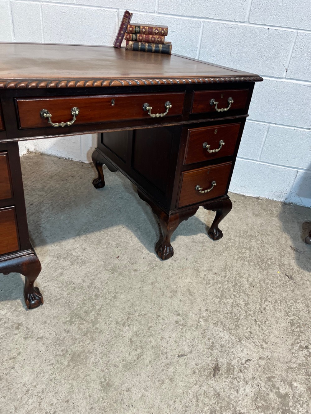 An early 20th-century dark mahogany pedestal writing desk featuring an inset leather top, brass swan-neck handles, seven drawers, and cabriole legs with ball and claw feet. View VIII