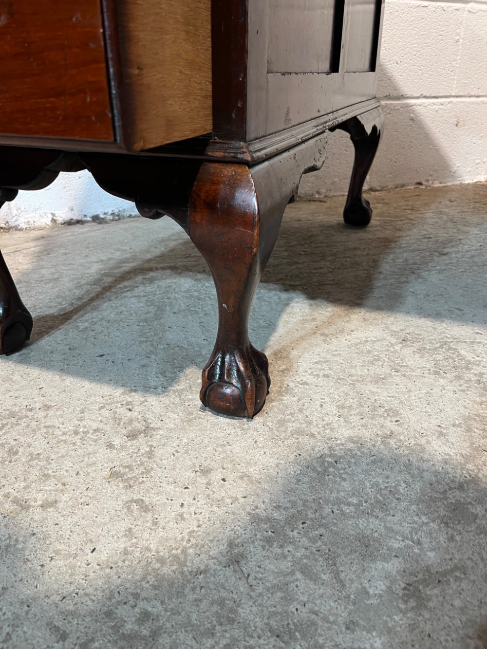 An early 20th-century dark mahogany pedestal writing desk featuring an inset leather top, brass swan-neck handles, seven drawers, and cabriole legs with ball and claw feet. View X