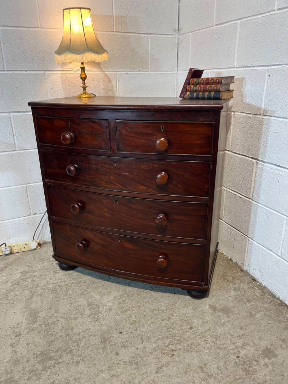 A 19th-century mahogany bowfront chest of drawers featuring two short drawers over three long drawers with turned wooden knobs and flame mahogany fronts. View II