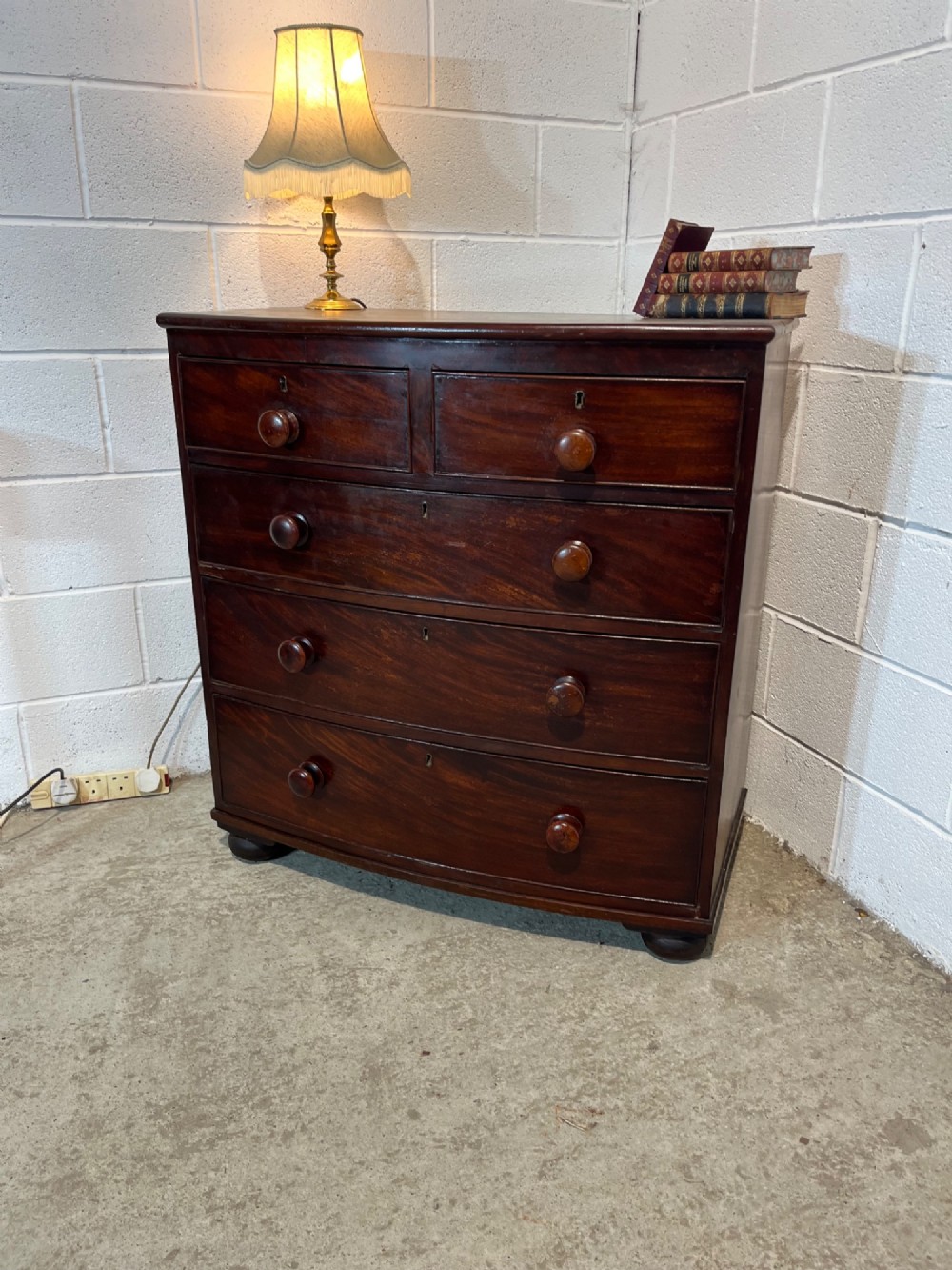 A 19th-century mahogany bowfront chest of drawers featuring two short drawers over three long drawers with turned wooden knobs and flame mahogany fronts. View III