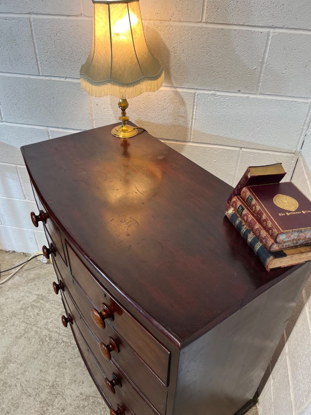 A 19th-century mahogany bowfront chest of drawers featuring two short drawers over three long drawers with turned wooden knobs and flame mahogany fronts. View V