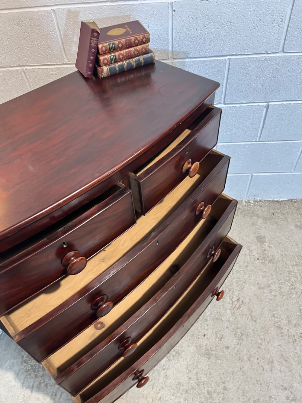 A 19th-century mahogany bowfront chest of drawers featuring two short drawers over three long drawers with turned wooden knobs and flame mahogany fronts. View VIII