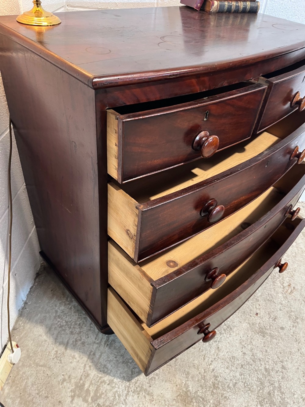 A 19th-century mahogany bowfront chest of drawers featuring two short drawers over three long drawers with turned wooden knobs and flame mahogany fronts. View IX