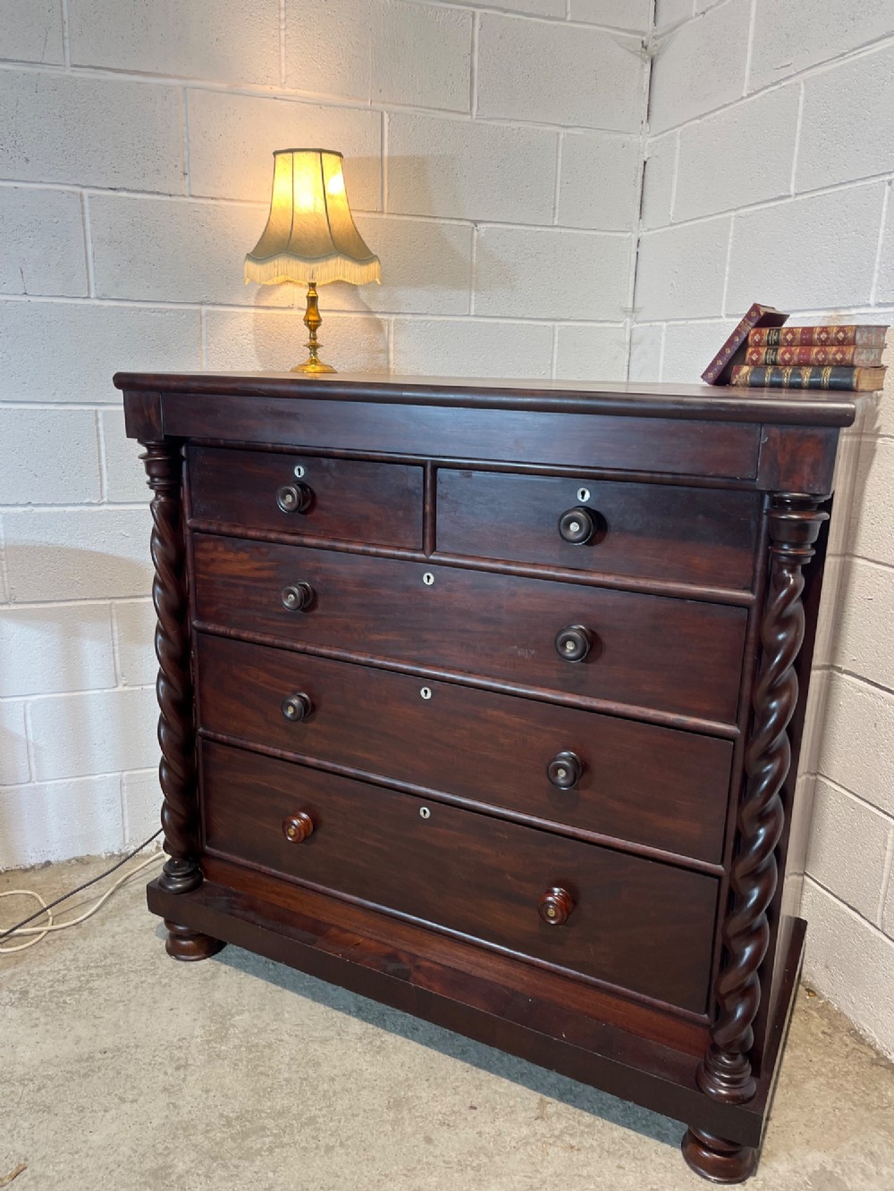 A 19th-century dark mahogany Scotch chest of drawers featuring spiral barley twist side columns, turned wooden knobs, and a heavy plinth base. View V