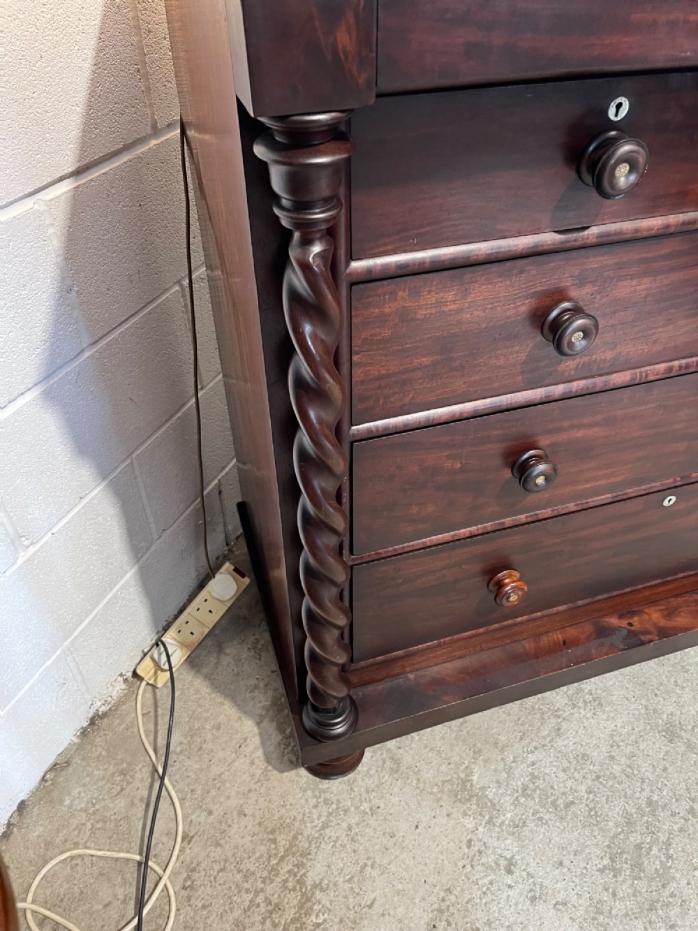 A 19th-century dark mahogany Scotch chest of drawers featuring spiral barley twist side columns, turned wooden knobs, and a heavy plinth base. View VII