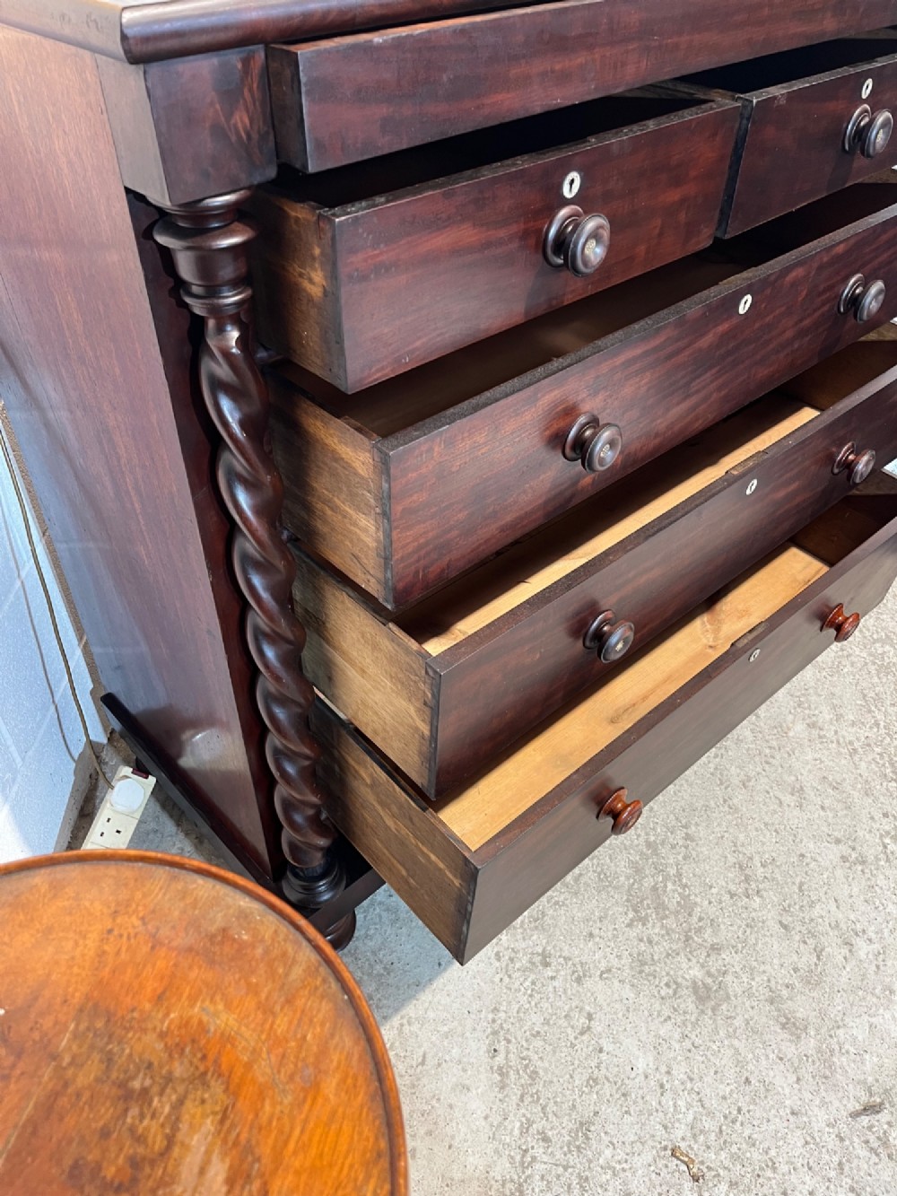 A 19th-century dark mahogany Scotch chest of drawers featuring spiral barley twist side columns, turned wooden knobs, and a heavy plinth base. View X