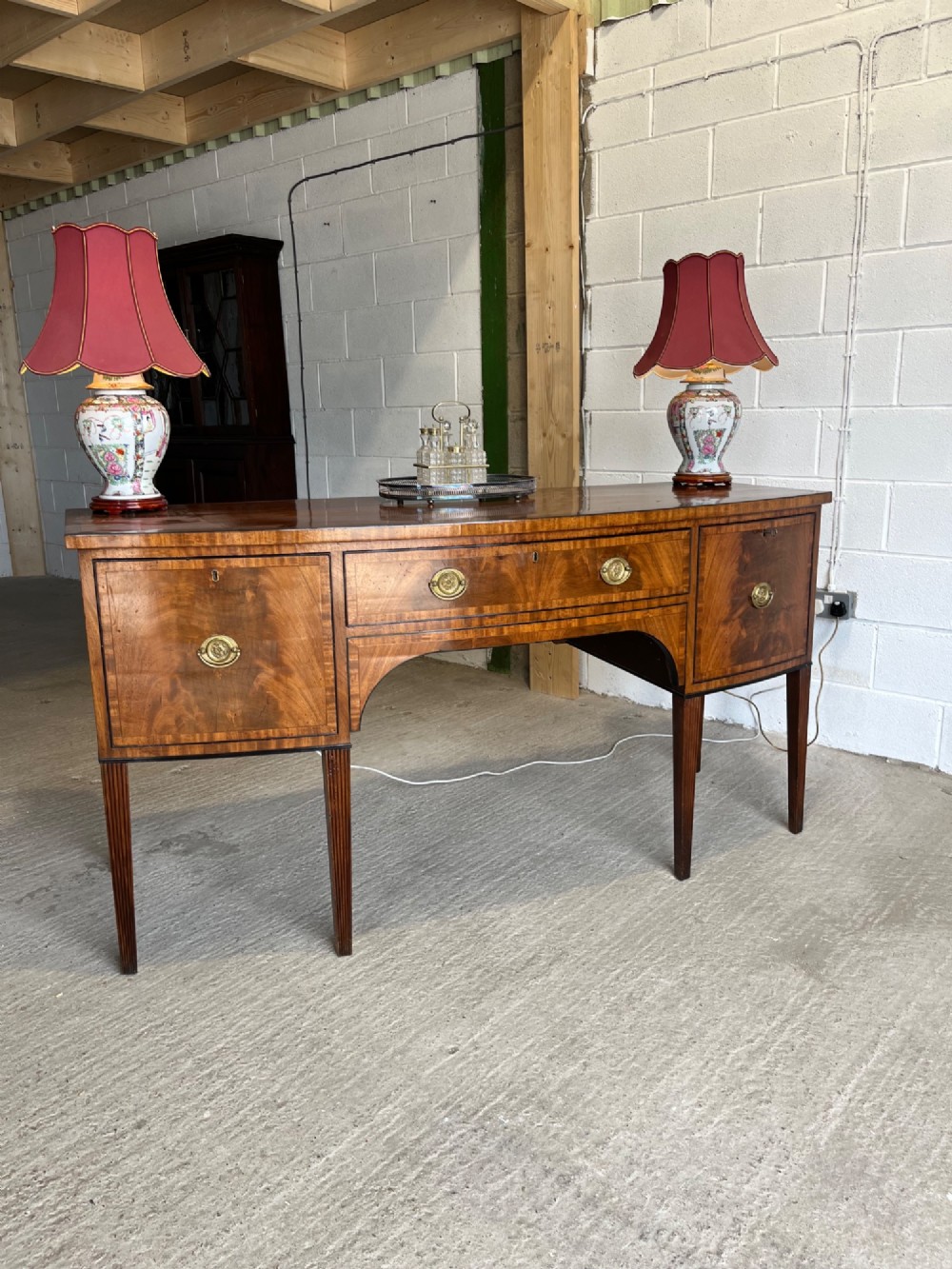 A Georgian mahogany sideboard featuring flame mahogany drawer fronts, brass ring handles, decorative line inlay, and fluted tapered legs. View II