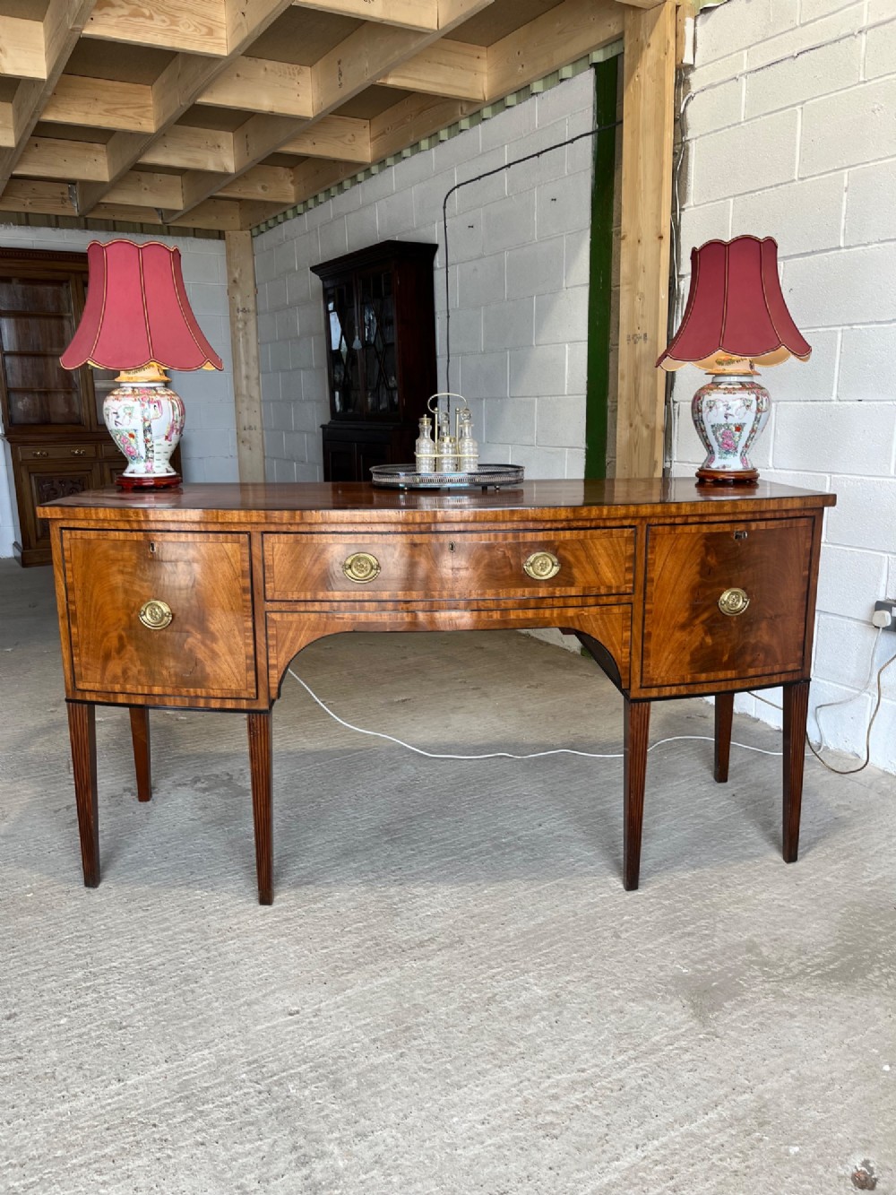 A Georgian mahogany sideboard featuring flame mahogany drawer fronts, brass ring handles, decorative line inlay, and fluted tapered legs. View III