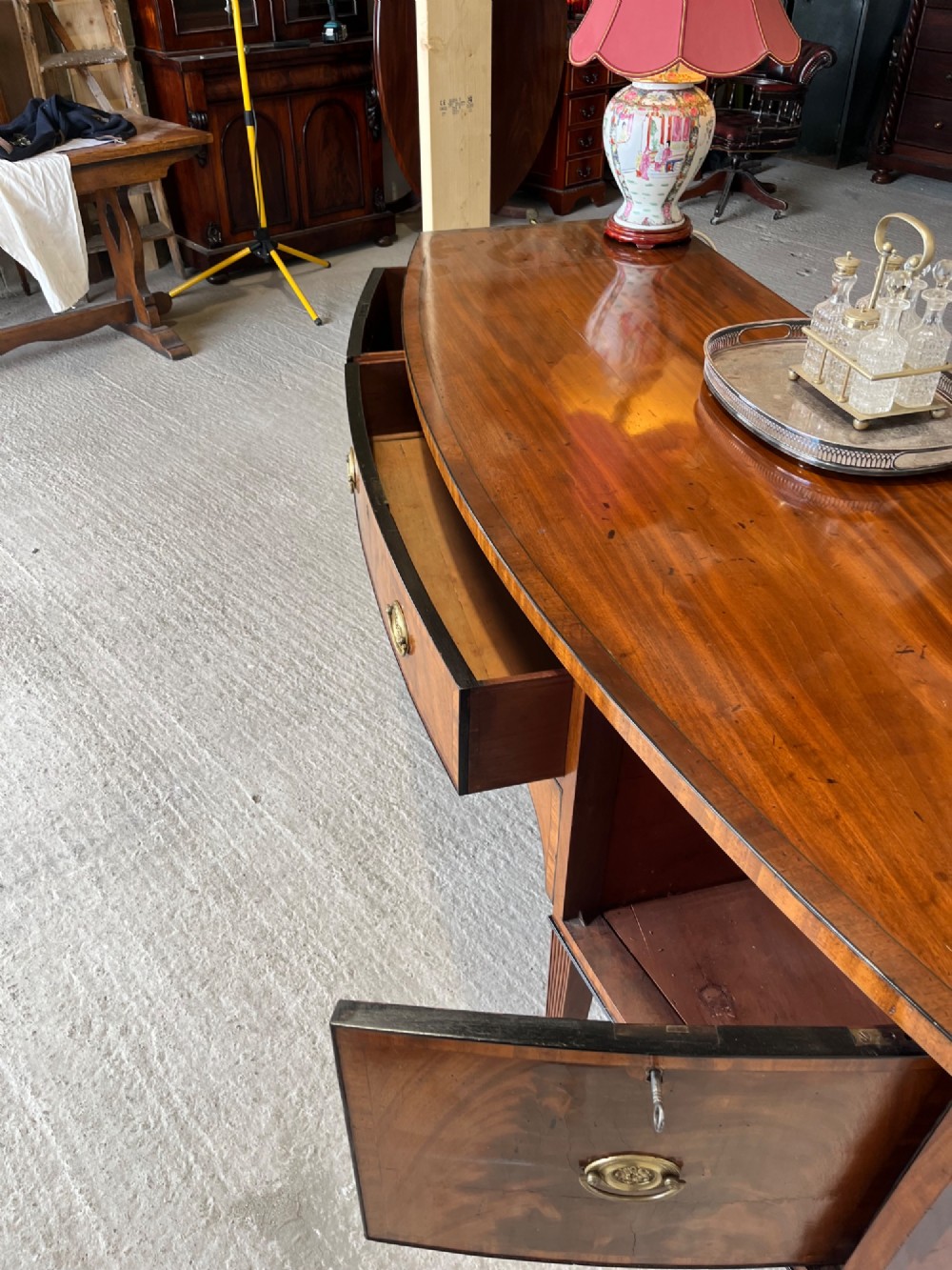 A Georgian mahogany sideboard featuring flame mahogany drawer fronts, brass ring handles, decorative line inlay, and fluted tapered legs. View VII