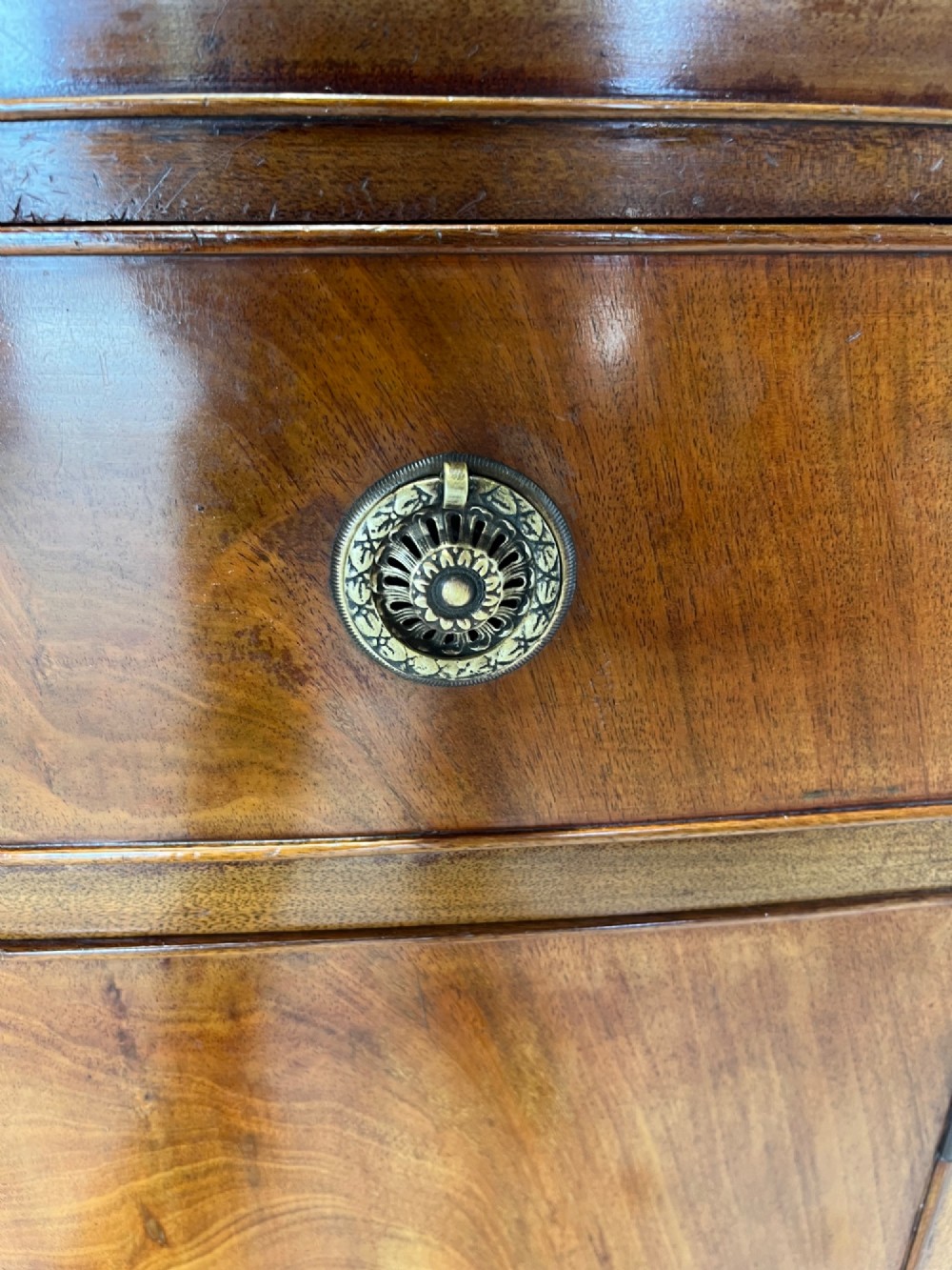 A late 19th-century mahogany cupboard featuring a single top drawer over a two-door cabinet with flame mahogany veneer panels and turned brass ring pull handles. View VIII