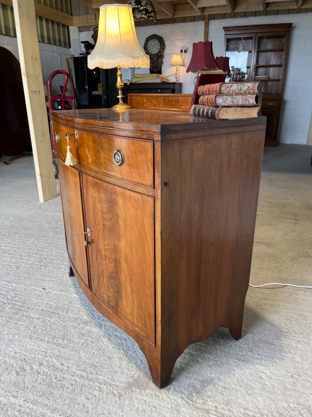 A late 19th-century mahogany cupboard featuring a single top drawer over a two-door cabinet with flame mahogany veneer panels and turned brass ring pull handles. View IX