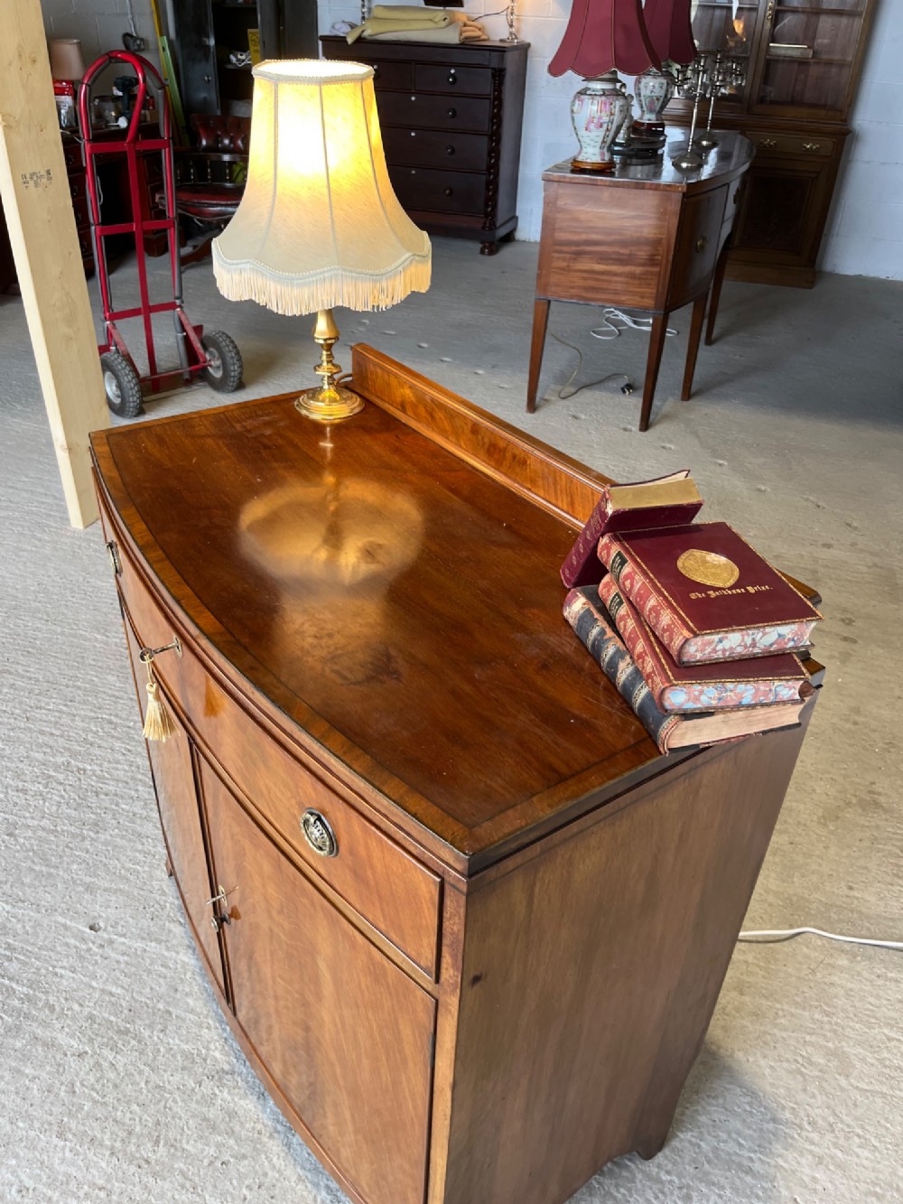 A late 19th-century mahogany cupboard featuring a single top drawer over a two-door cabinet with flame mahogany veneer panels and turned brass ring pull handles. View X