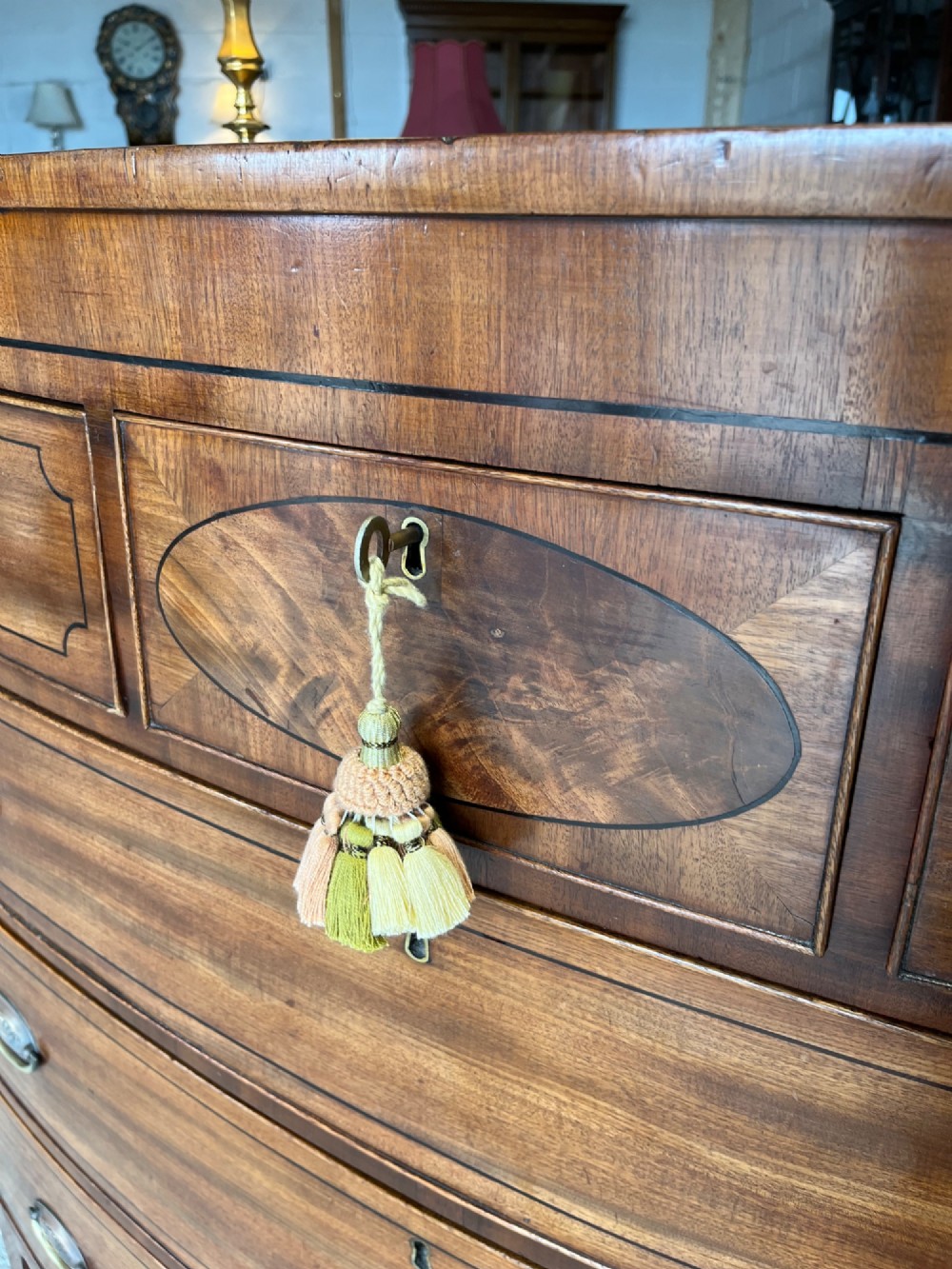 A 19th-century mahogany bowfront chest of drawers featuring a curved front with multiple drawers, brass oval drop handles, keyhole escutcheons, and bracket feet. View IX