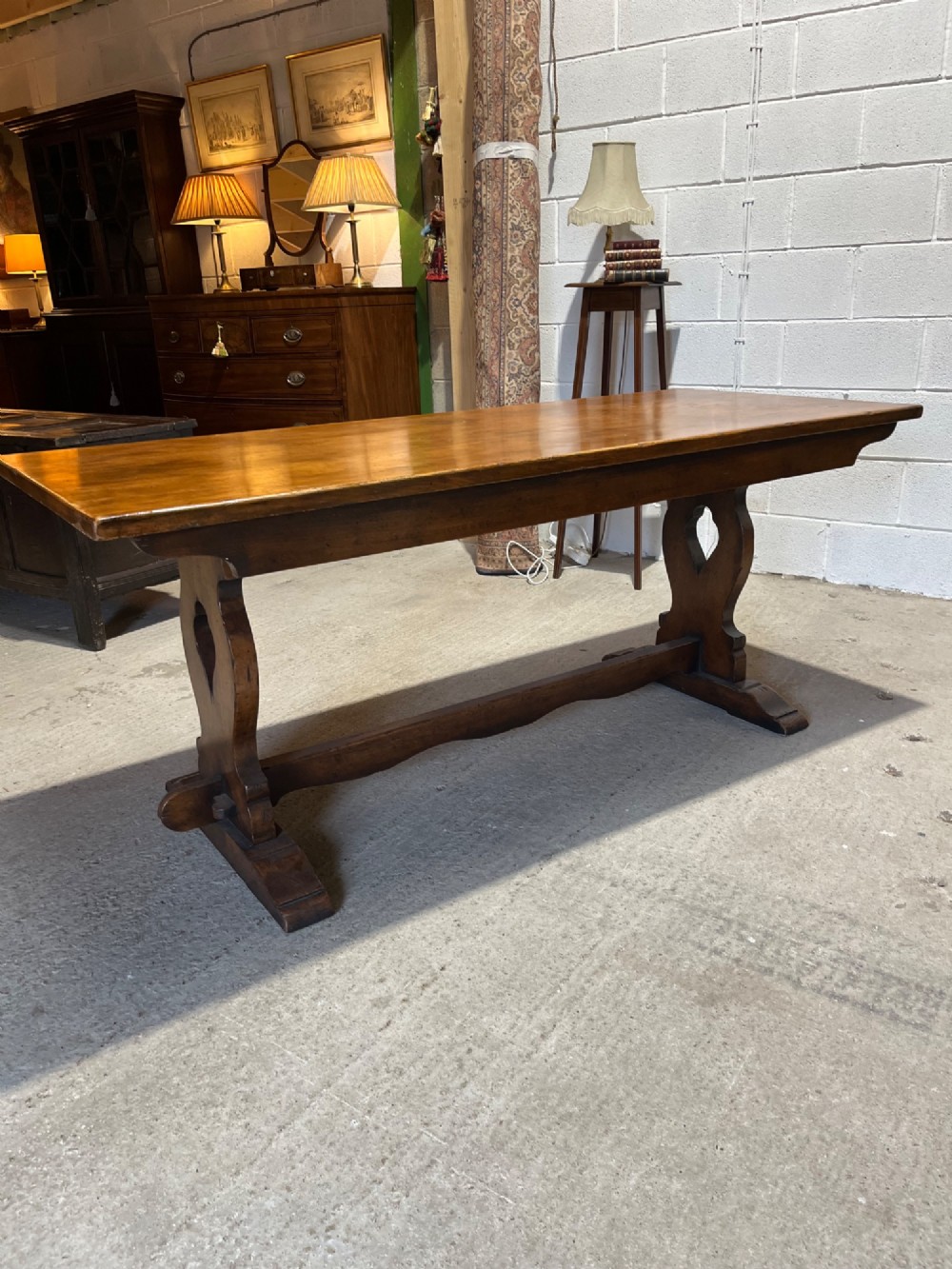 A long solid oak refectory table with a trestle base, surrounded by eight ladderback dining chairs with woven rush seats. View II