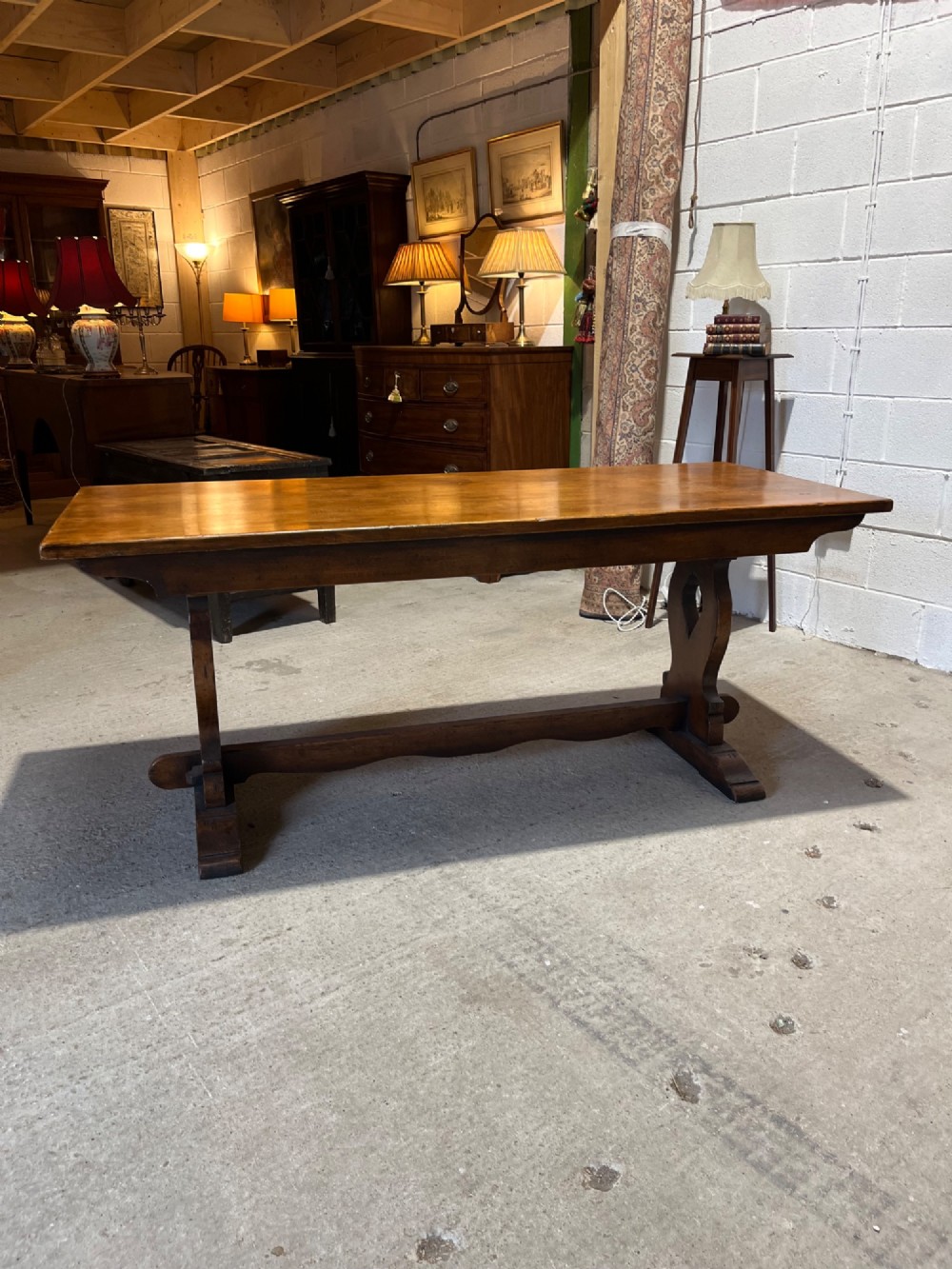 A long solid oak refectory table with a trestle base, surrounded by eight ladderback dining chairs with woven rush seats. View VI