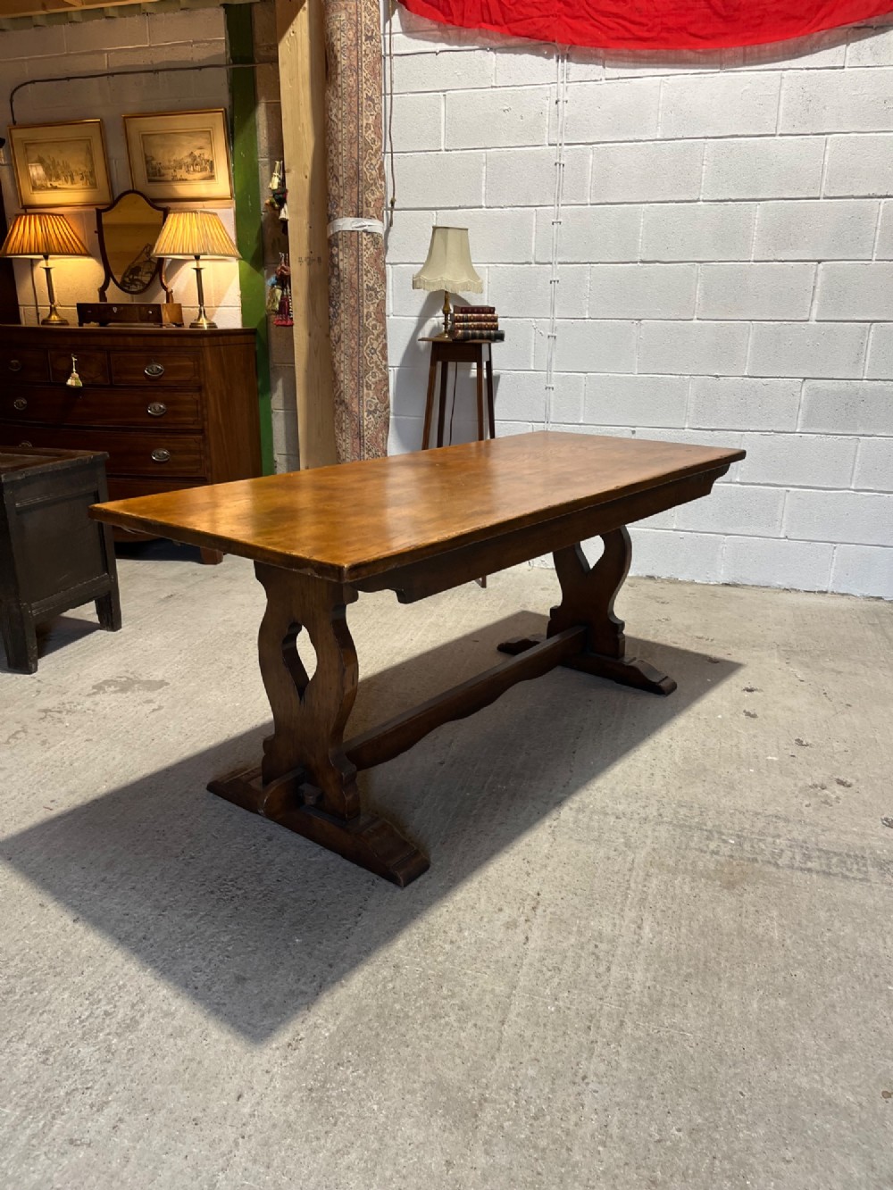 A long solid oak refectory table with a trestle base, surrounded by eight ladderback dining chairs with woven rush seats. View VII