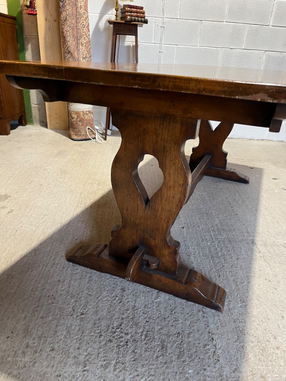 A long solid oak refectory table with a trestle base, surrounded by eight ladderback dining chairs with woven rush seats. View IX