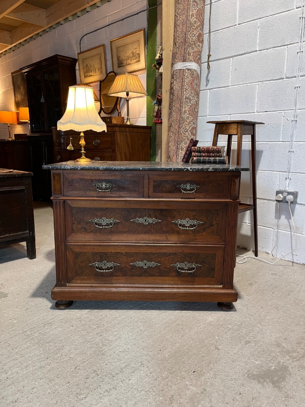 An antique 19th-century French walnut chest of drawers featuring a dark grey marble top and ornate brass handles. View II
