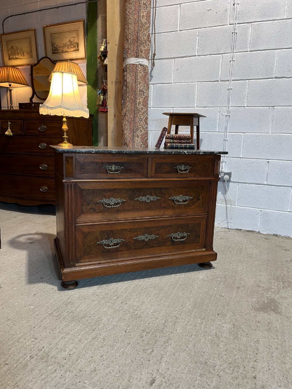An antique 19th-century French walnut chest of drawers featuring a dark grey marble top and ornate brass handles. View III