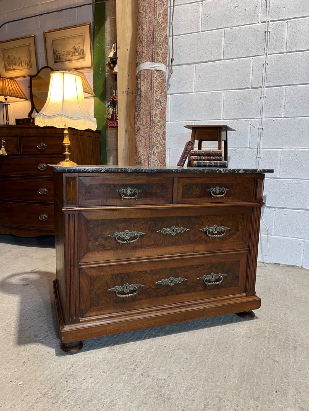 An antique 19th-century French walnut chest of drawers featuring a dark grey marble top and ornate brass handles. View IV