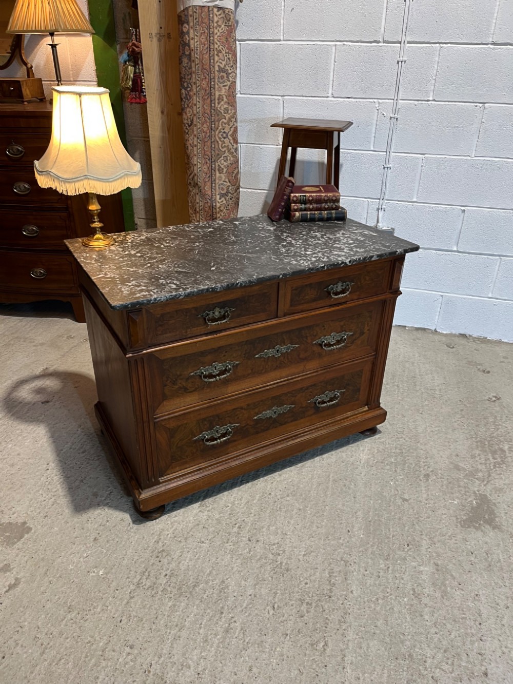 An antique 19th-century French walnut chest of drawers featuring a dark grey marble top and ornate brass handles. View V
