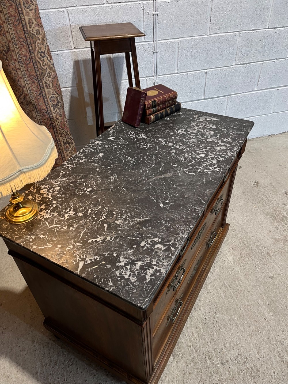 An antique 19th-century French walnut chest of drawers featuring a dark grey marble top and ornate brass handles. View VI