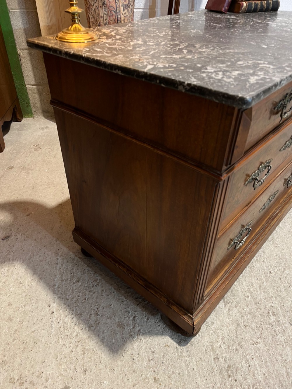 An antique 19th-century French walnut chest of drawers featuring a dark grey marble top and ornate brass handles. View VII