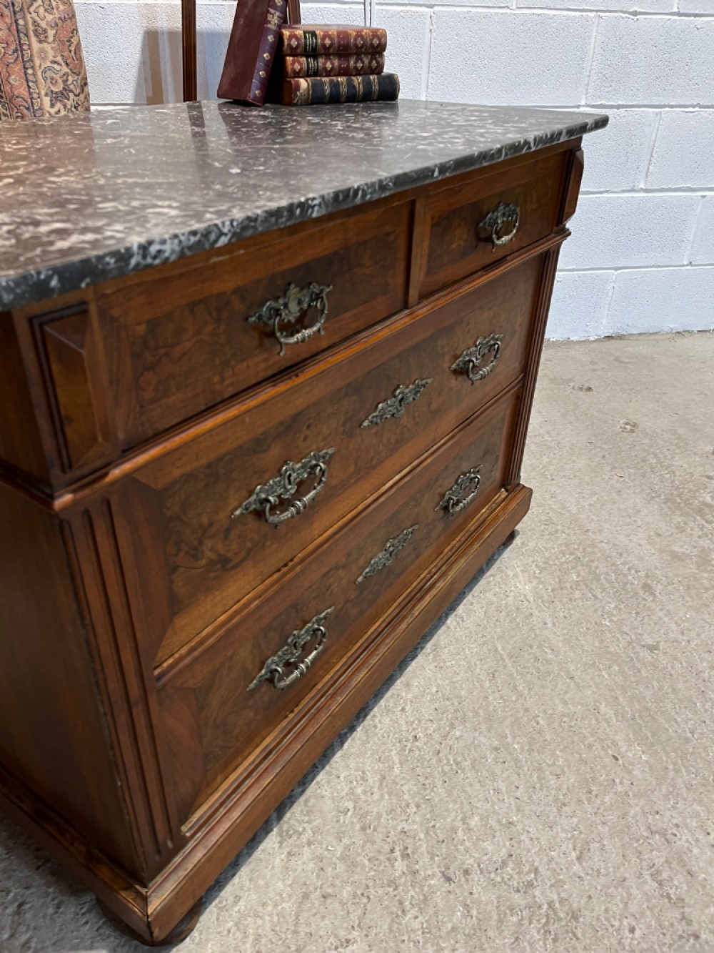 An antique 19th-century French walnut chest of drawers featuring a dark grey marble top and ornate brass handles. View VIII